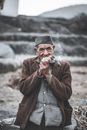 Thoughtful elderly ethnic man smoking pipe in countryside