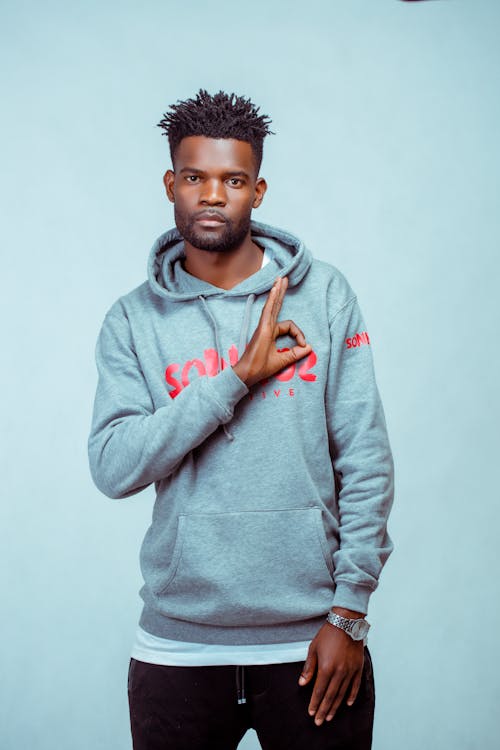 Photograph of a Man in a Gray Hoodie Doing a Hand Sign