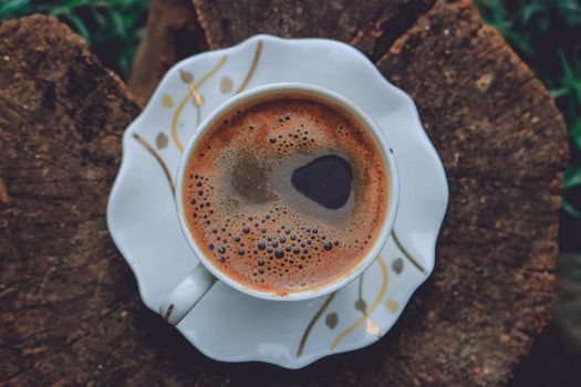 Cup of hot black coffee on tree trunk