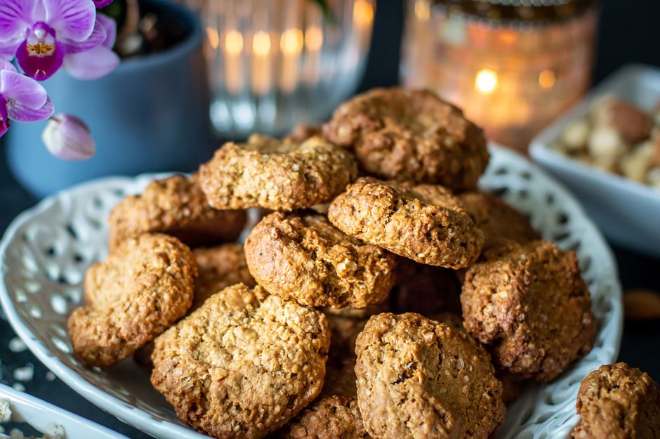 A stack of thick, soft baked oatmeal cookies with cracked tops, one broken in half showing a tender, moist center.