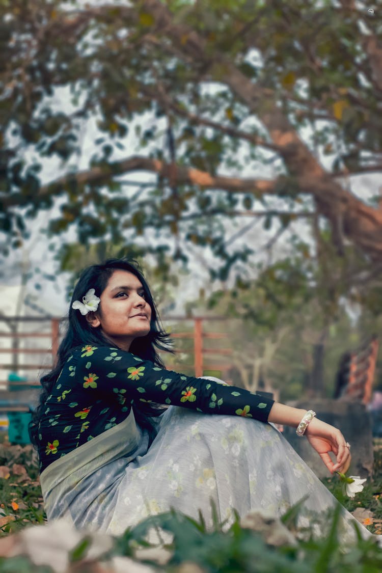 Calm Ethnic Woman Sitting On Grass In Garden