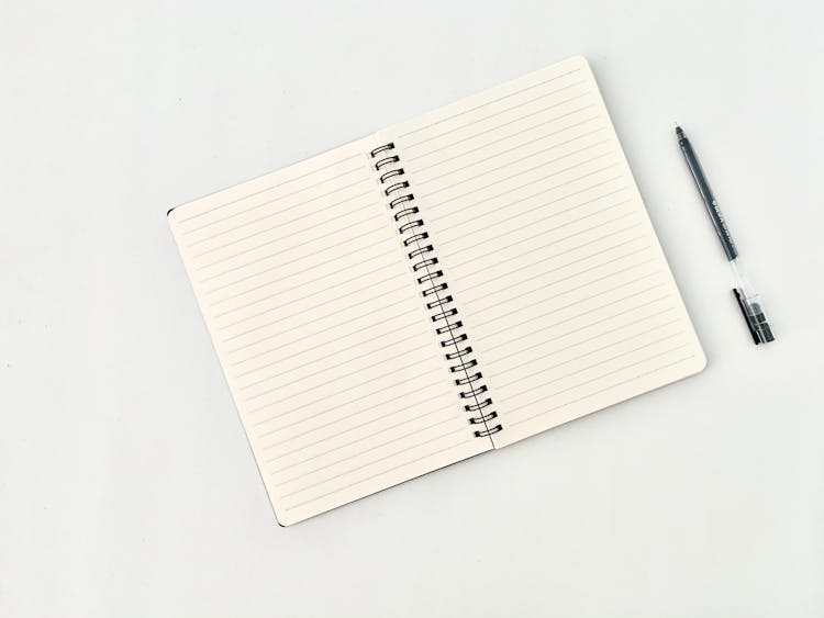 Spiral Notepad With Lines Near Pen On White Background