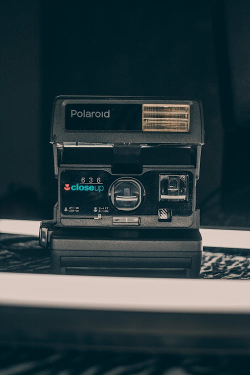 Old fashioned instant camera with focus lens and instant print placed on desk in studio
