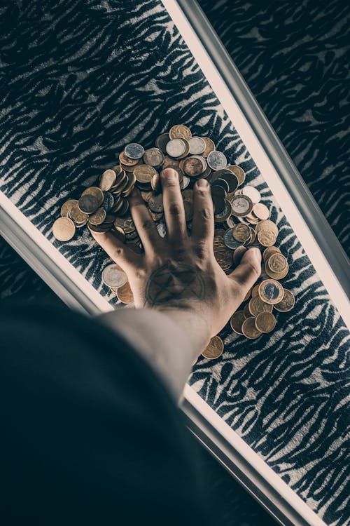 Crop man touching pile of coins