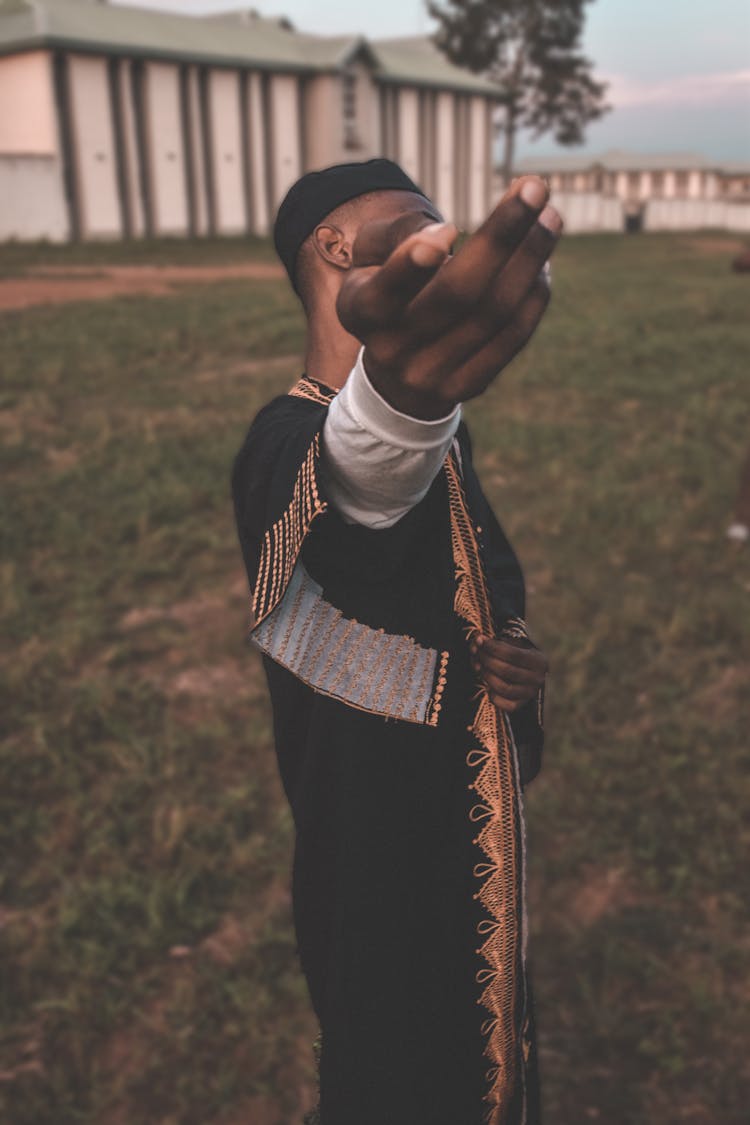 Anonymous Ethnic Man Standing In Courtyard With Outstretched Arm