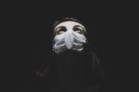 在黑暗的环境中，一名戴着口罩的女子抬头仰望，象征着大流行时代