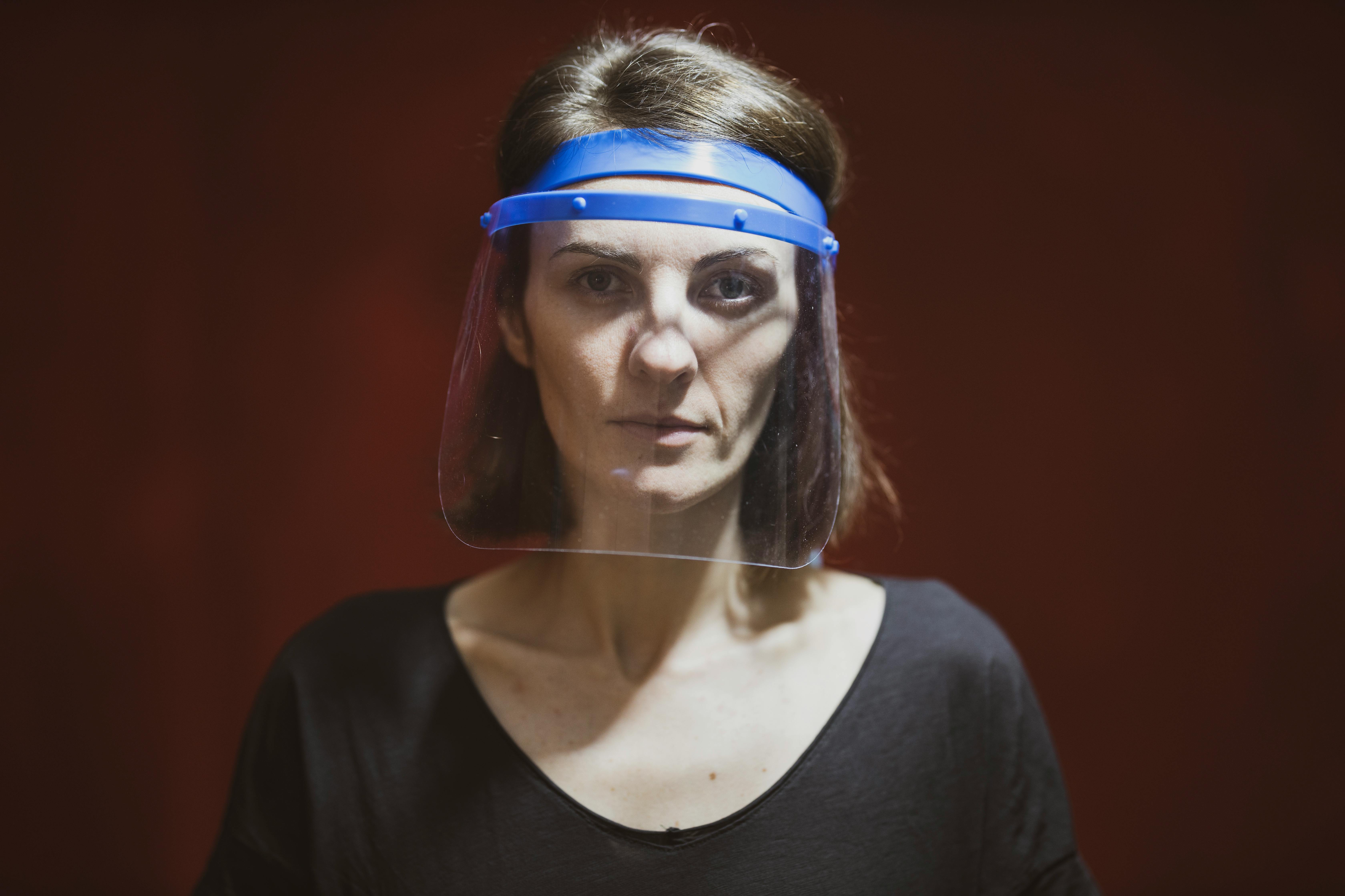 Close-up of a woman wearing a face shield for protection in a studio setting.