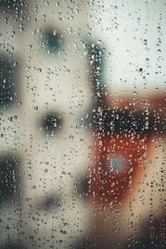 Closeup of water drops on transparent misted glass during rain as abstract background