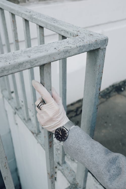 Person With Latex Gloves Holding a Fence