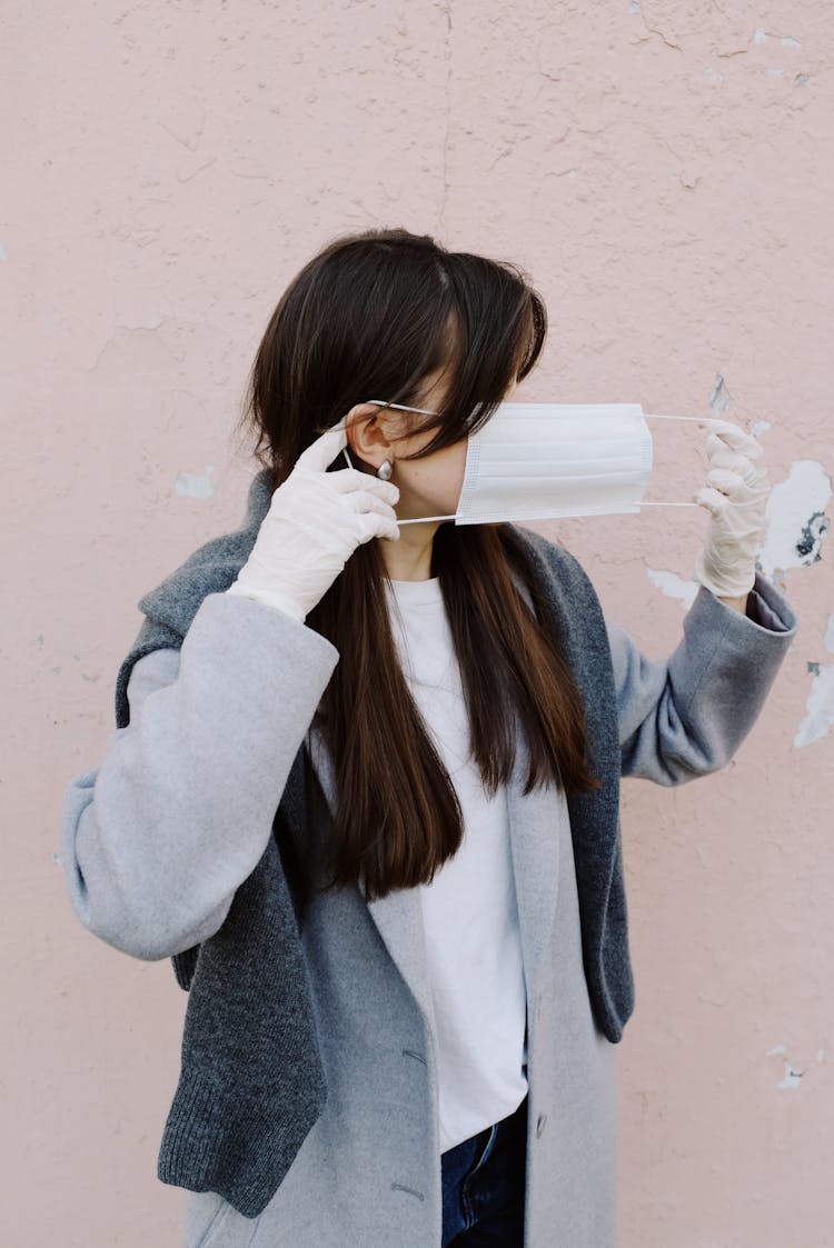 Woman With Latex Gloves Putting On A Face Mask