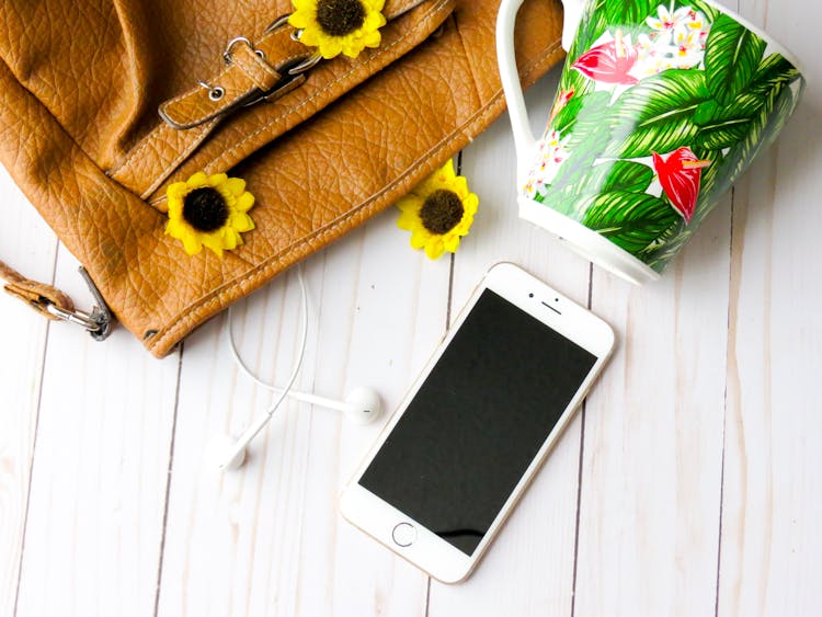 Gold Iphone 6 Beside Brown Leather Bag