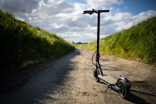 Electric scooter on rural road in grassland against cloudy blue sky