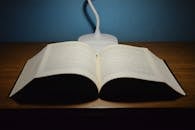 Opened book placed on wooden table near modern lamp