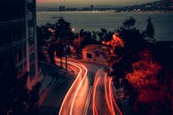 An Aerial Photography of a Road Between Trees and Building at Night