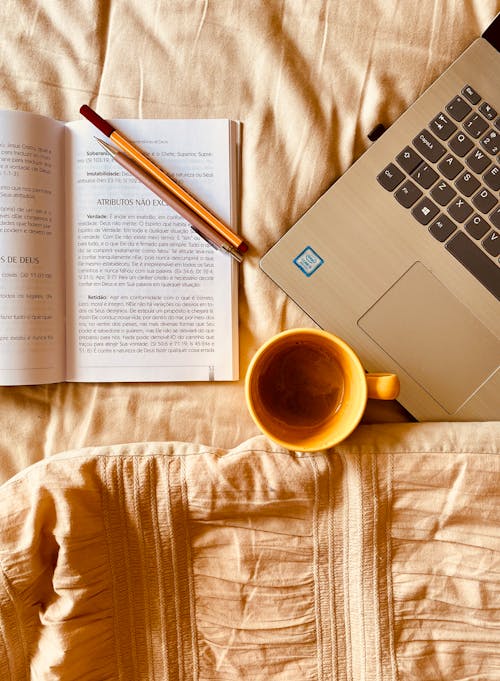 Coffee, Book and Laptop on Bed
