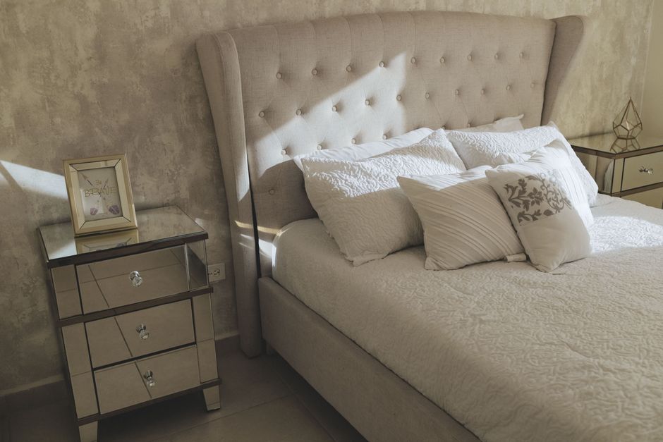 Cosy bedroom with a stylish headboard, pillows and mirrored side tables.