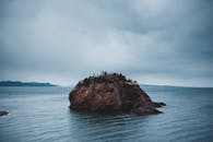 Rocky formation in sea on overcast day