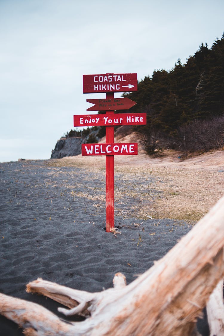 Red Sign With Hiking Directions On Beach