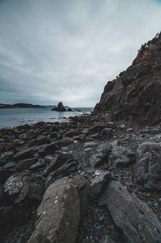 Empty gray rocky coast and stony cliff against calm sea and cloudy sky. empty, gray, rocky
