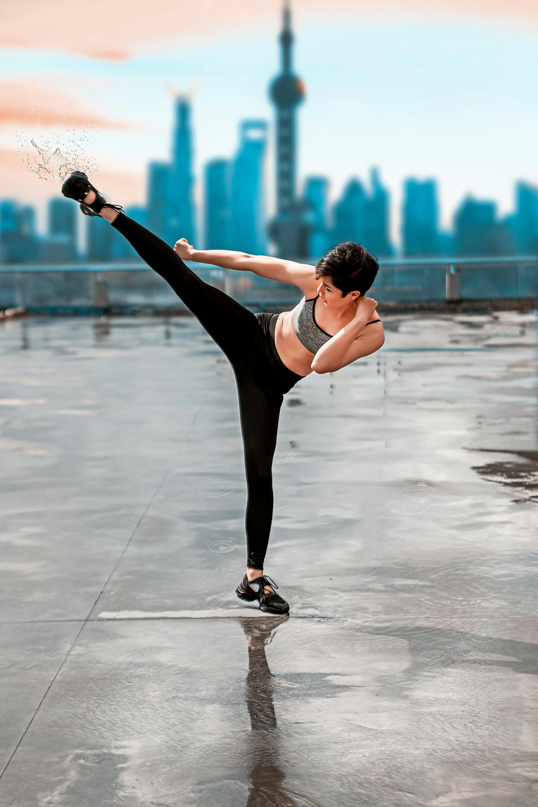 a woman in gray tank top and black leggings in kicking position