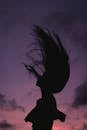 Silhouette of woman against sunset sky
