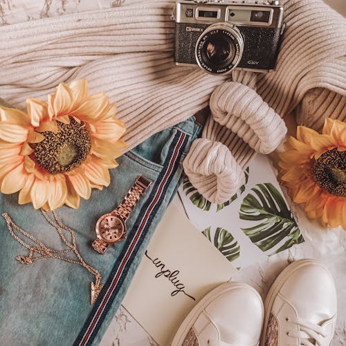 Free Top view layout of jeans sunflowers vintage photo camera and accessories placed on jeans and sweater near sneakers Stock Photo