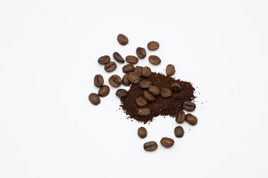A detailed view of roasted coffee beans and ground coffee on a white surface, showcasing texture.