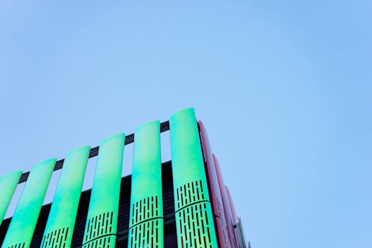 现代建筑立面以充满活力的绿色和红色为主，独特的建筑风格映衬在清澈的蓝天下