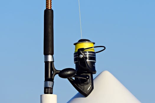 Detailed view of a fishing rod and reel set against a clear blue sky, highlighting outdoor leisure.