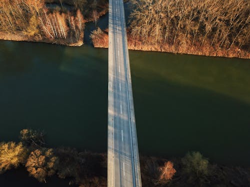 Bridge with empty road over river between autumn trees