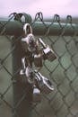 Silver Padlocks on Green Steel Fence