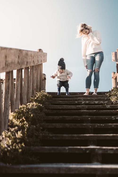 Free A mother and child enjoying a sunny outdoor moment on wooden stairs, expressing bonding and joy. Stock Photo