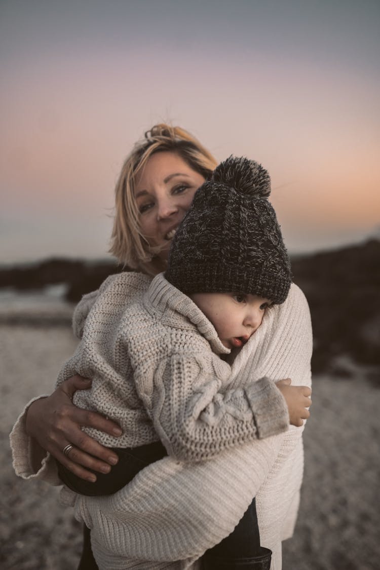 Photo Of A Woman Carrying Her Baby In Knitted Clothes