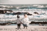 一对母子在宁静的海滩上，面朝海浪，共享美好时光