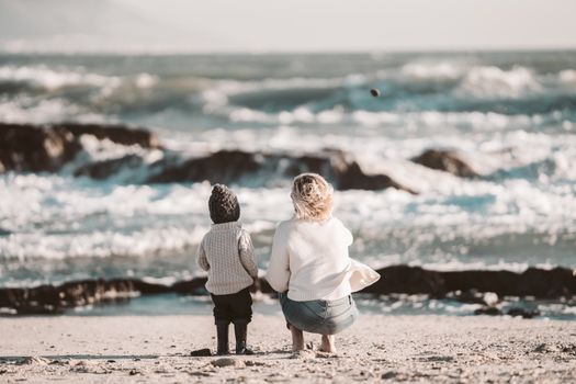 一对母子在宁静的海滩上，面朝海浪，共享美好时光