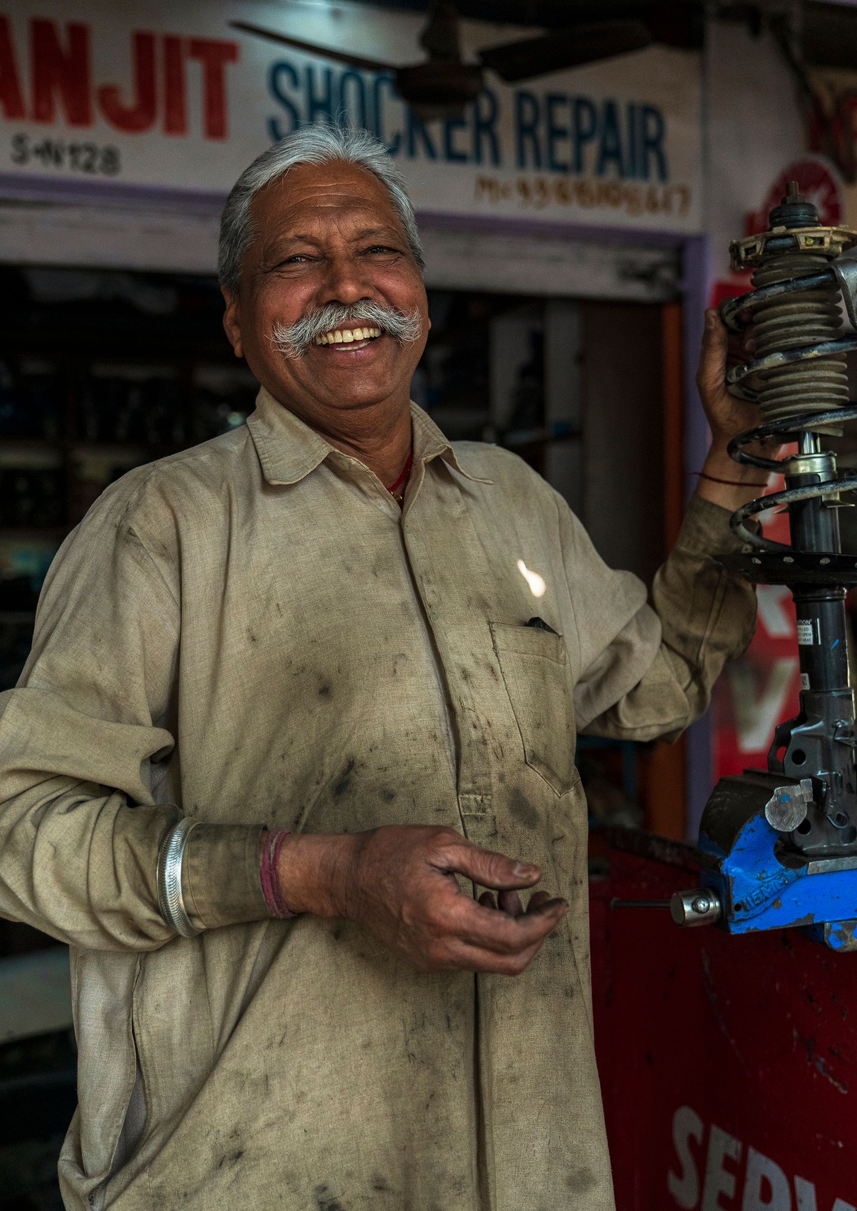 A smiling mechanic in overalls in his repair shop