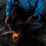 Tongs holding bright stock over the anvil, photo by Nishant Aneja on Pexels