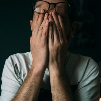 室内，一名男子双手捂脸，神情悲伤或失望