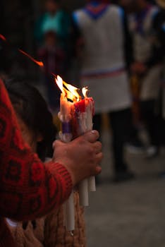 Close-up of hand holding lit candles during a traditional ceremony in Trujillo, Peru.