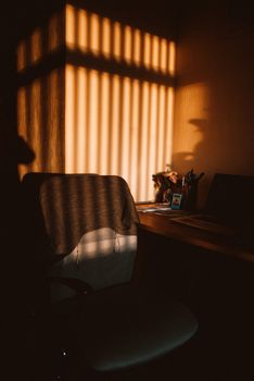 Warm sunlight casting shadows in a cozy home office nook, creating a serene ambiance.