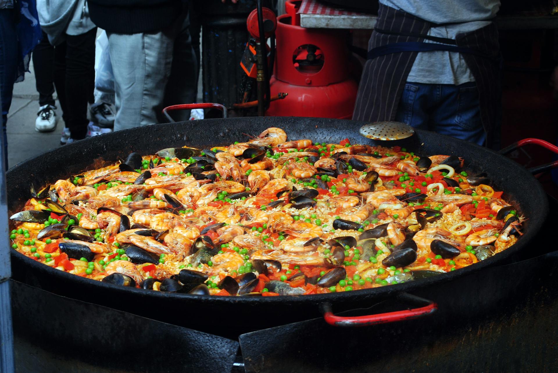 From above of traditional tasty Spanish dish with rice and bright chopped vegetables decorated with shellfish