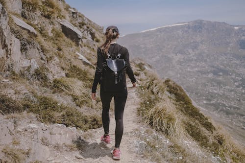 Woman in Black Long Sleeve Shirt and Black Pants Standing on Rocky Hill