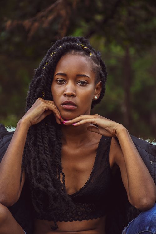 Free Young pensive African American female in earring and stylish outfit looking at camera while touching face Stock Photo