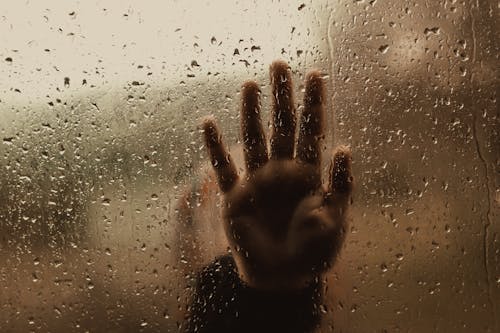 Free Hand of unrecognizable person behind wet window Stock Photo