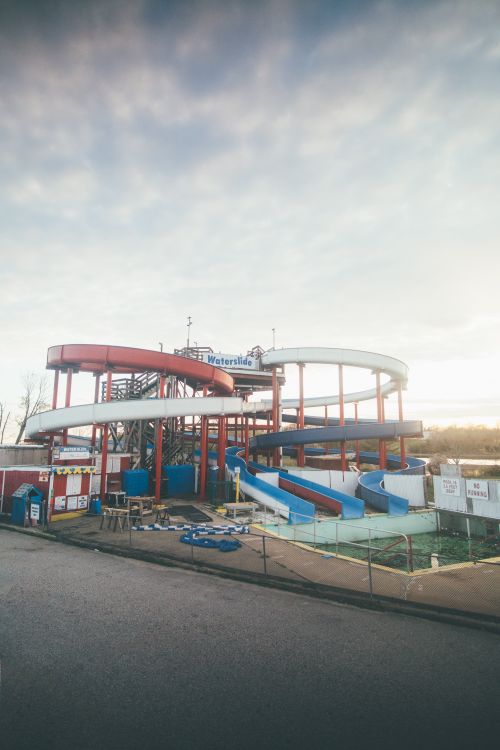 Free An empty water park with slides under a cloudy sky, exuding a nostalgic and abandoned feel. Stock Photo