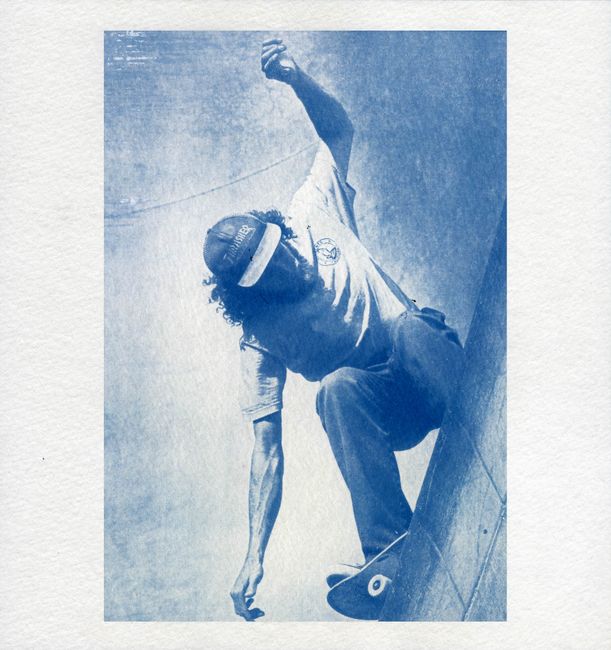 Dynamic cyanotype of a skateboarder in motion at a skate park, low angle view.