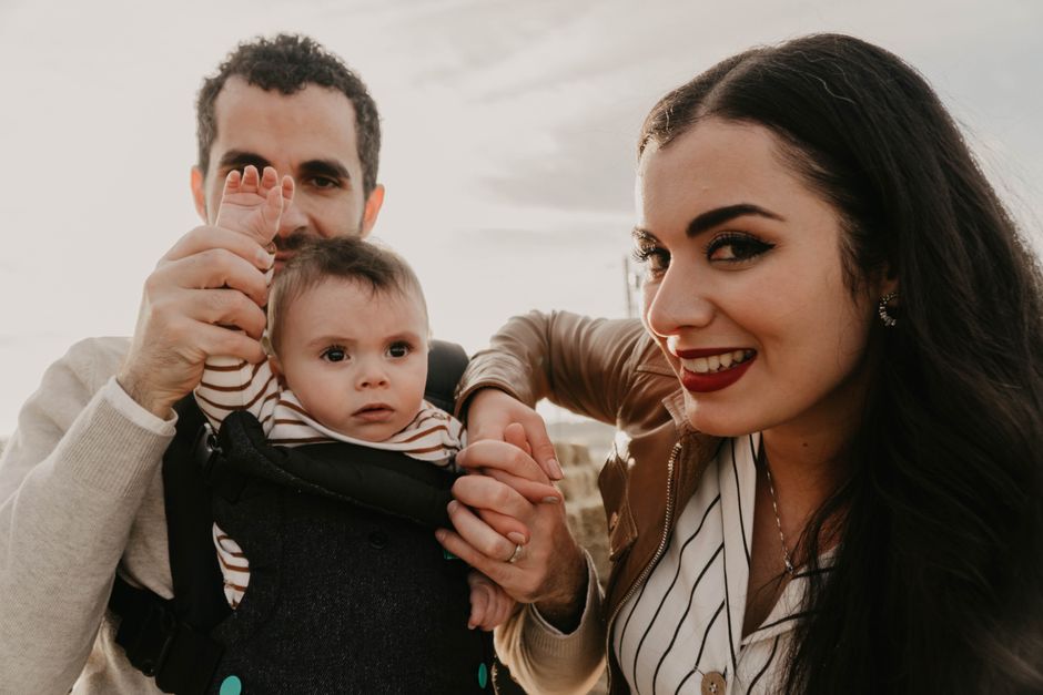 Loving family enjoying time together outdoors with their baby in a carrier.