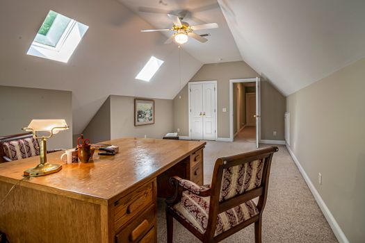 A serene attic office space with natural lighting, featuring a wooden desk and vintage chair.