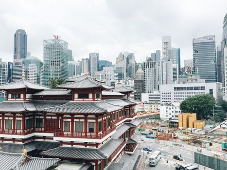 从现代多层住宅背后，古老的亚洲房屋立面在城里多云的天空下显现