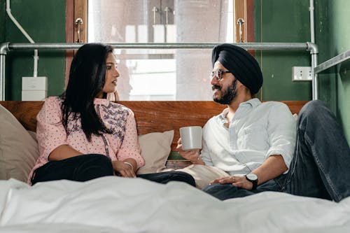 Smiling couple resting on bed and talking